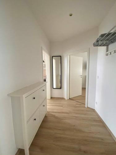 een witte kamer met een dressoir en een hal bij Schöne 3-Zimmer Ferienwohnung im Süden von Leipzig EG in Leipzig