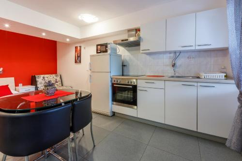 a kitchen with white cabinets and a red wall at Apartmani Višnja in Crikvenica