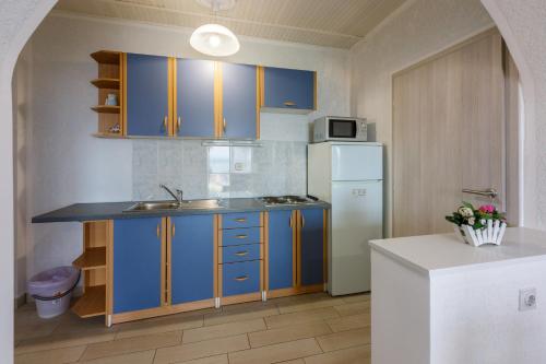 a kitchen with blue cabinets and a white refrigerator at Apartmani Višnja in Crikvenica