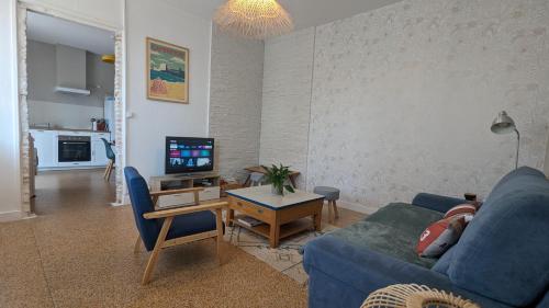 salon z niebieską kanapą i telewizorem w obiekcie Andernos-Maison de centre-ville avec jardin w mieście Andernos-les-Bains