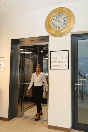 a woman standing in a elevator with a clock on the wall at Karls Hotel in Sigmaringen