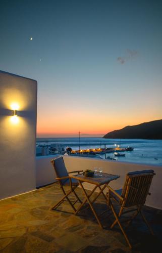 einen Tisch und Stühle auf einem Balkon mit Blick auf den Sonnenuntergang in der Unterkunft ERISIMO SUITES in Aegiali