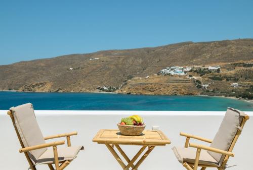2 Stühle und ein Tisch mit einer Obstschale in der Unterkunft ERISIMO SUITES in Aegiali