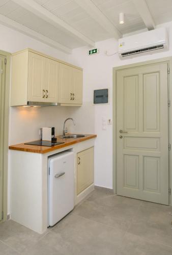 cocina con armarios blancos, fregadero y puerta en ERISIMO SUITES, en Egíali