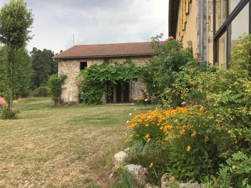 ein altes Steinhaus mit Blumen im Hof in der Unterkunft Le Bos Clard in Félines