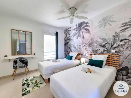 two beds in a room with a ceiling fan at T3 - Tropical Lodge - 3 étoiles - 65m2 - Saint-Pierre in Saint-Pierre