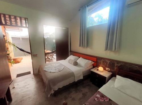 a small bedroom with a bed and a window at Portal do Sabiá Maresias in Maresias