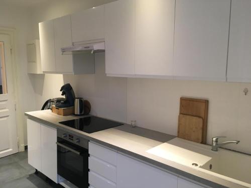 a kitchen with white cabinets and a black stove top oven at Le Vauban - appartement 2 chambres, salon, cuisine équipée, parking et wifi gratuit in Mulhouse