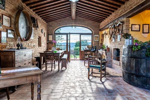 MarcianoにあるIl Querciolo - Azienda biologica, Agriturismo e Cantinaのテーブルと椅子、大きな窓が備わる広い客室です。