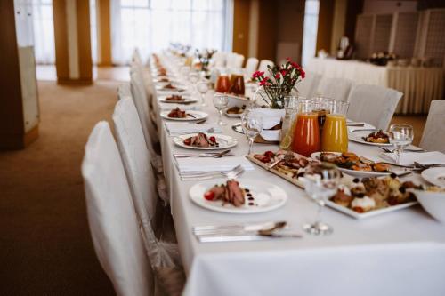 a long white table with plates of food on it at Hotel Great Polonia Velvet Suwałki in Suwałki