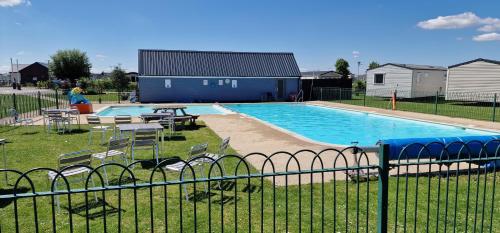 uma piscina com mesas e cadeiras ao lado de uma cerca em Ashdale By Sea em Whitstable