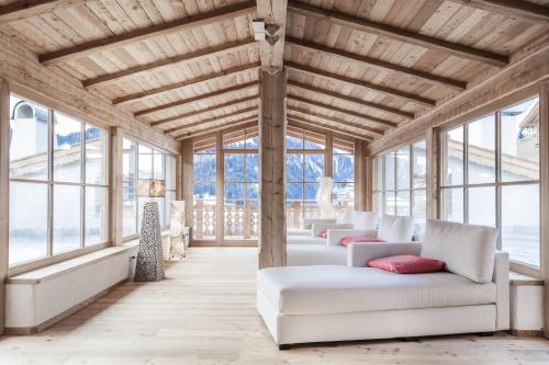 una sala de estar con sofás blancos y ventanas en Dorfhotel Beludei, en Santa Cristina Valgardena