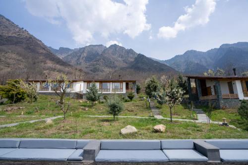 een huis in een veld met bergen op de achtergrond bij Qayaam Gah in Srinagar