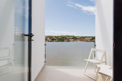 a white chair in a room with a view of the ocean at Memmo Baleeira - Design Hotels in Sagres