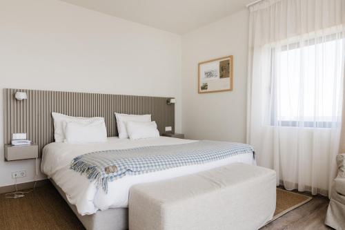a white bedroom with a large bed and a window at Memmo Baleeira - Design Hotels in Sagres