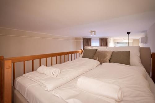 een bed met witte lakens en kussens erop bij K7 - Boutique Apartments, Best Location. By BQA in Boedapest
