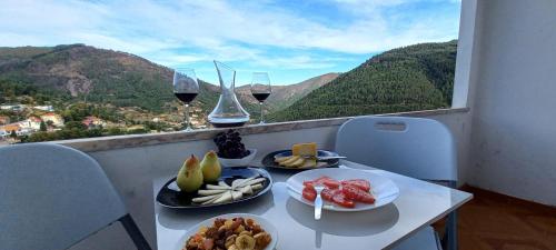 a table with two plates of food and glasses of wine at Moradia Félix - Apartamento Félix in Manteigas