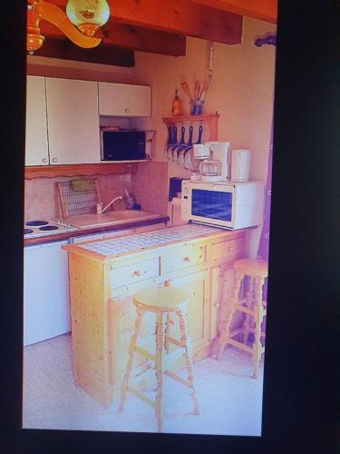a kitchen with a counter and two stools in it at Catarmina in Saint-Pancrace