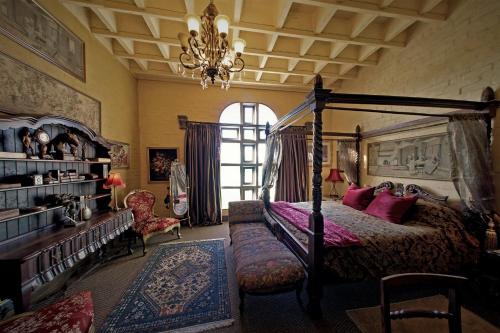 een slaapkamer met een hemelbed en een kroonluchter bij Bygracealone Manor in Outeniekwa