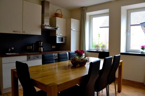 uma cozinha com uma mesa de madeira com cadeiras à volta em De Moolt Vakantiewoningen em Eckelrade