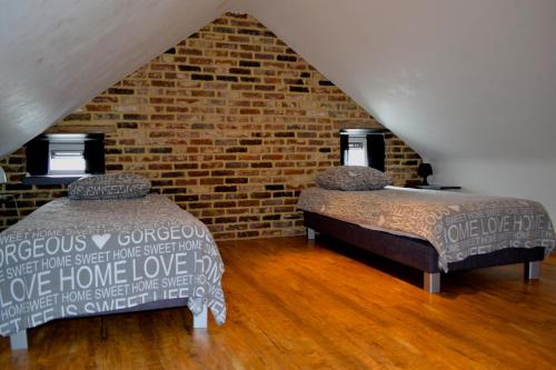 two beds in a room with a brick wall at De Moolt Vakantiewoningen in Eckelrade