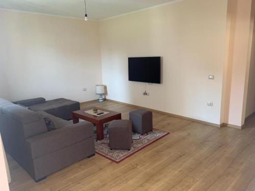 een woonkamer met een bank en een flatscreen-tv bij Apartment with garden in the center of Durres in Durrës
