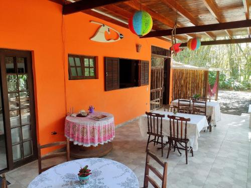 a patio with tables and chairs and an orange wall at Portal do Sabiá Maresias in Maresias
