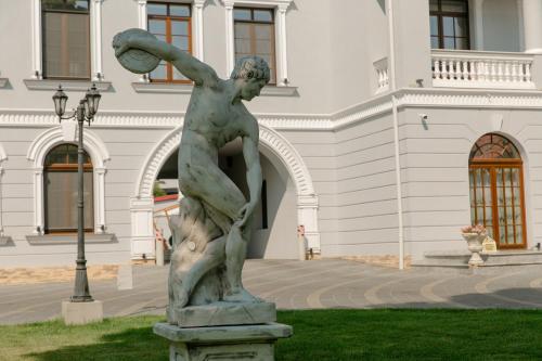 a statue of a man holding a ball in front of a building at Muller Hotel Boutique & Spa in Galaţi