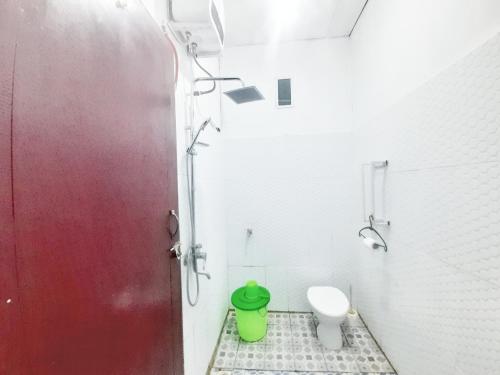 baño con aseo y cubo de basura verde en Baronda Guest House, en Sorong