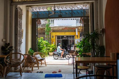 een persoon op een fiets in een kamer met stoelen en tafels bij The Real Place Hostel in Battambang