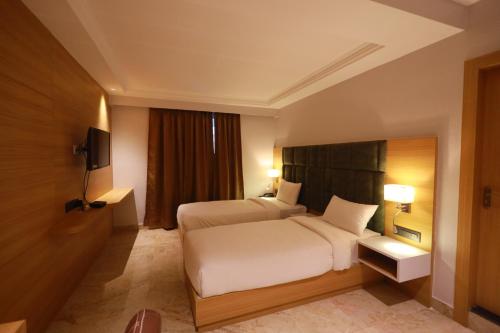 une chambre d'hôtel avec un lit et une télévision dans l'établissement LUXUS INN, à Dhanbād