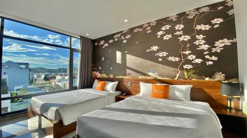 two beds in a room with a mural of flowers at Bel-Air Hotel in Quy Nhon