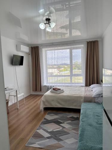 een slaapkamer met een bed, een raam en een bureau bij Promenad Burabay 45P in Borovoye