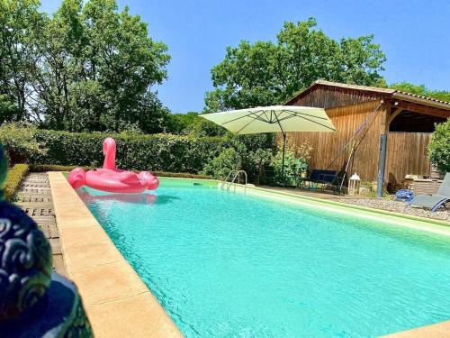 - une piscine avec un radeau gonflable rose et un parasol dans l'établissement Villa Sylva, à Sarlat-la-Canéda