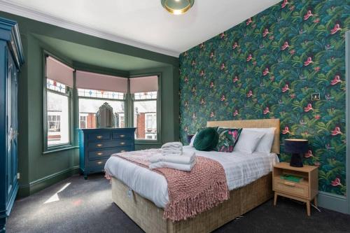 a bedroom with a bed with a floral wall at Big House, and a lot to give! in Middlesbrough