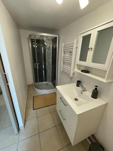 une salle de bain blanche avec un lavabo et une douche dans l'établissement Maison de vacances familiale, à Ouistreham