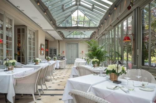 um restaurante com mesas e cadeiras brancas e um tecto de vidro em Brenners Park-Hotel & Spa - an Oetker Collection Hotel em Baden-Baden