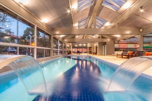 a swimming pool with two chairs in a building at Hotel Laghetto Gramado in Gramado