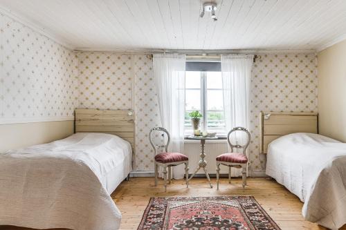 2 letti in una camera da letto con tavolo e 2 sedie di Stubbegården - Unique swedish style a Vadstena