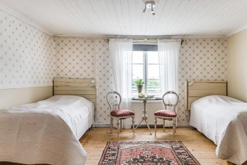 two beds in a bedroom with a table and two chairs at Stubbegården - Unique swedish style in Vadstena