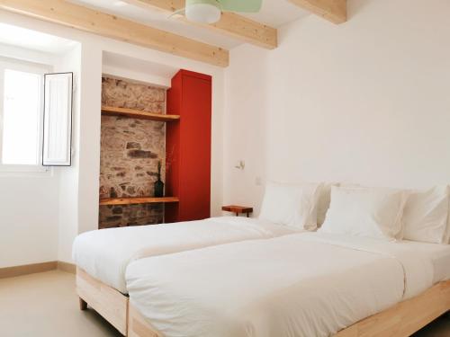 two beds in a white bedroom with a red wall at AL MAR Guesthouse in São Luis