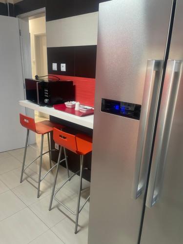 eine Küche mit einem Kühlschrank aus Edelstahl und roten Schränken in der Unterkunft Apartamento remodelado no Seixal in Seixal