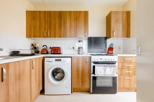 a kitchen with a washing machine and wooden cabinets at One Bed (Entire Flat) - 25 mins from London Bridge in London