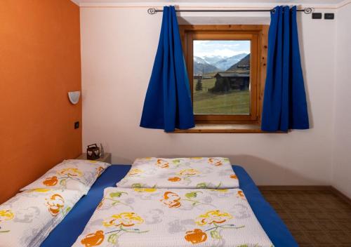 a bedroom with a bed and a window with blue curtains at Appartamenti Astra in Livigno