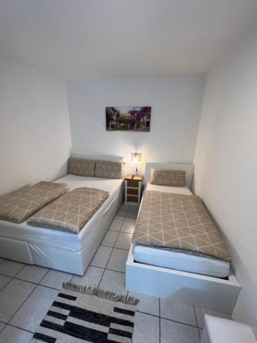 2 camas en una habitación pequeña con sofá cama en Alex Apartments, en Solingen