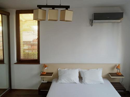 1 dormitorio con 1 cama blanca grande y TV en Голям апартамент с прекрасна гледка кьм морето en Ravda