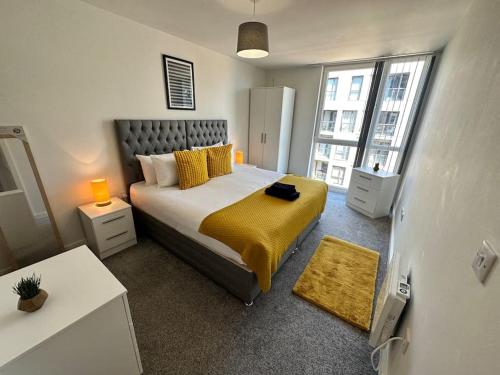 1 dormitorio con 1 cama grande con almohadas amarillas en Cosy 2 Bed Apt Sleeps 4+Balcony en Mánchester
