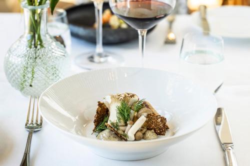 a white bowl of food on a table with wine glasses at Stella Maris in Svendborg