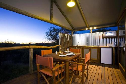 einen Holztisch und Stühle auf einer Terrasse in der Unterkunft Windhoek Game Camp in Lafrenz Township