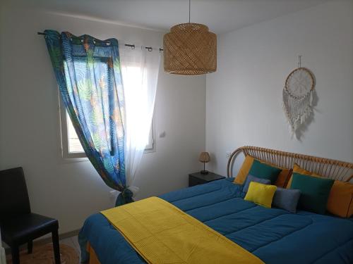a bedroom with a blue and yellow bed and a window at L'hippocampe in Gruissan
